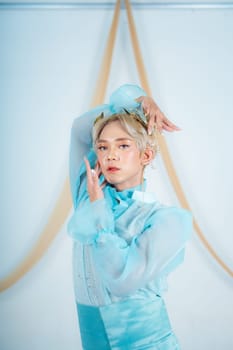a princess with a blue dress and blonde hair posing very beautifully in front of a white background