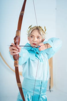 a princess in a blue dress pulling a bow with her hand in a white room