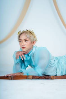 a princess in a blue dress posing on the floor with a bow in a white room