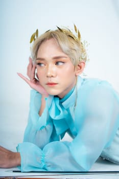 a woman with flawless makeup wearing a golden crown on her blonde hair in a white room