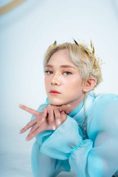 a woman with flawless makeup wearing a golden crown on her blonde hair in a white room