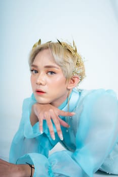 a woman with blonde hair and a face full of makeup poses beautifully with a bow in a white studio