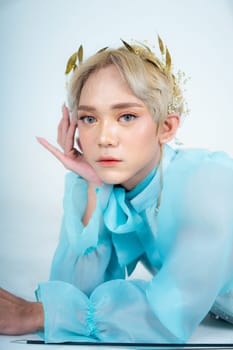 a woman with flawless makeup wearing a golden crown on her blonde hair in a white room