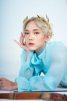 a woman with flawless makeup wearing a golden crown on her blonde hair in a white room