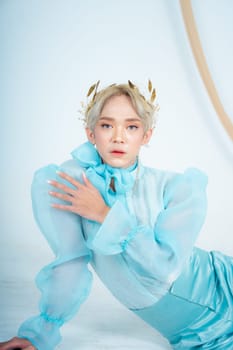 a royal princess posing with a golden crown and blonde hair very cutely in a white room