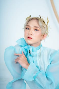 a royal princess posing with a golden crown and blonde hair very cutely in a white room