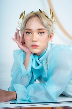 a woman with flawless makeup wearing a golden crown on her blonde hair in a white room