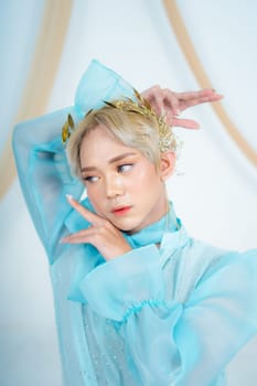 a royal princess in a blue dress posing with her hands very elegantly in a white palace