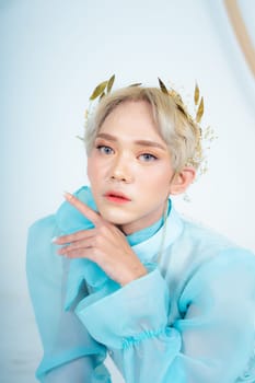 a royal princess posing with a golden crown and blonde hair very cutely in a white room
