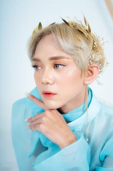 a royal princess posing with a golden crown and blonde hair very cutely in a white room