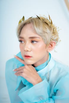 a royal princess posing with a golden crown and blonde hair very cutely in a white room