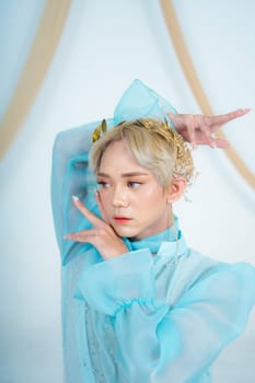 a royal princess in a blue dress posing with her hands very elegantly in a white palace