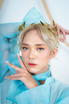 a royal princess in a blue dress posing with her hands very elegantly in a white palace