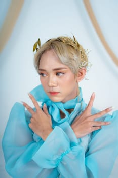 a royal princess in a blue dress posing with her hands very elegantly in a white palace
