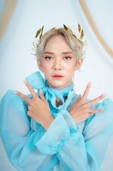 a royal princess in a blue dress posing with her hands very elegantly in a white palace