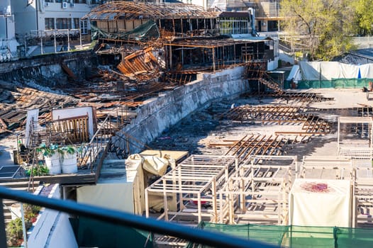 Damaged buildings after a fire. Consequences of a fire in the city. Burnt buildings of a restaurant, cafe or shopping center. estoration work is underway in the foreground