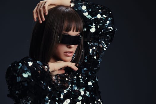 Woman, sequinned top, sunglasses a woman in a sparkling sequinned top and stylish sunglasses stands against a black background, her hands on her head and her head tilted to the side, exuding