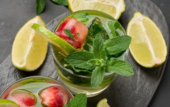 Refreshing mojito cocktail with lime, mint, strawberry, and ice on dark background, top view