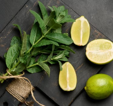 Bunch of fresh green mint on wooden board and lime wedges, top view. Cocktail ingredient