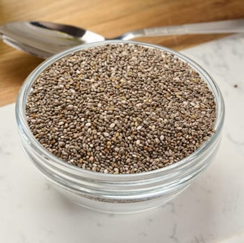Clear glass bowl filled with dry chia seeds, top view