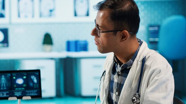 Indian healthcare expert sharing medical expertise with a patient in clinic, reviewing x ray scans and MRI diagnostics to focus on accurate treatment and recovery. Insurance check up. Camera A.