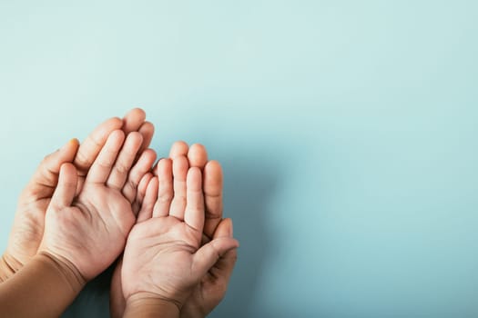 Top view studio shot, Family hands stacked against an isolated background. Parents and child hold empty space expressing support and love on Family and Parents Day.