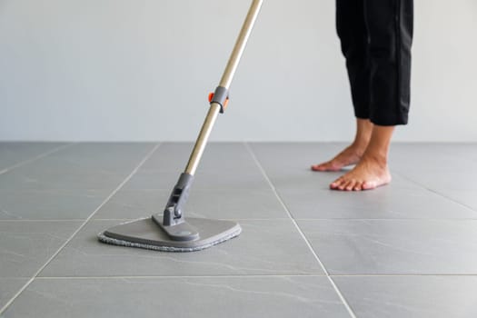 Woman mops the indoor floor, cleaning the front area of her home with a mop and rag. Housewife dedicated to maintaining cleanliness. Represents professional housekeeping and house maintenance concepts