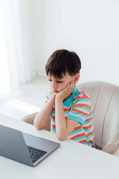 Boy schoolboy studying at a desk with a laptop online