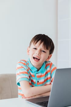 Boy schoolboy studying at a desk with a laptop online