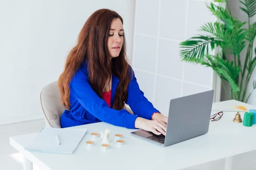 Women brunette woman in blue business suit at desk with laptop online