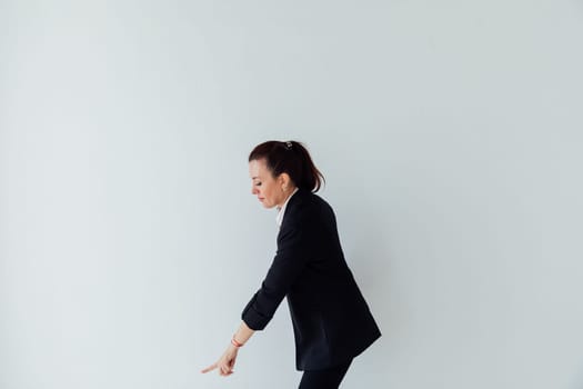 Brunette woman in business suit showing direction with her hand on white background
