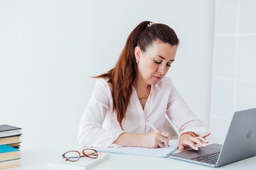 Brunette woman working at office desk with laptop online