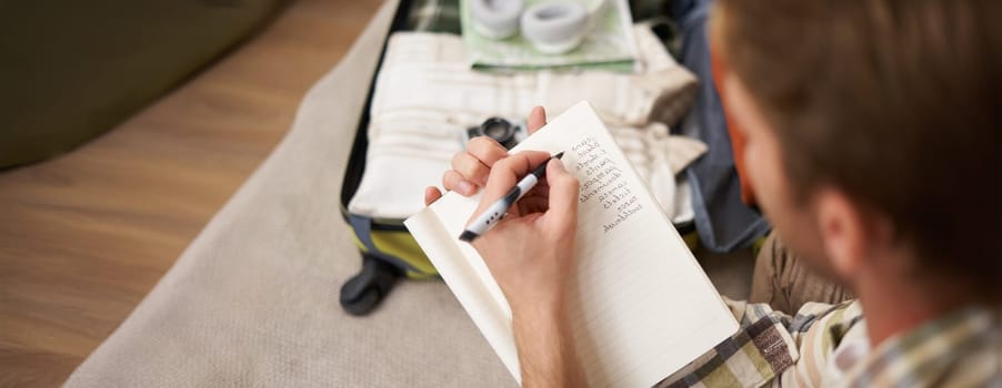 Close up portrait of man going through check-list, packing for holiday, looking at items he wants to bring on vacation.