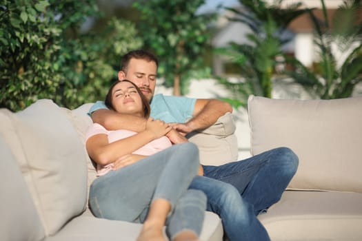 Couple sleeping together sitting in an exterior couch in a terrace at home