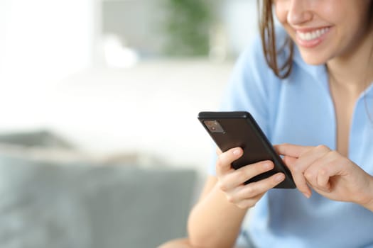 Close up of a happy woman holding and using smart phone at home