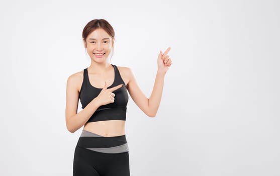 Fit and full of life, woman raises her hand to point above while another point adds flair to her confident pose in gym-ready sportswear, active and healthy lifestyle. isolated white background