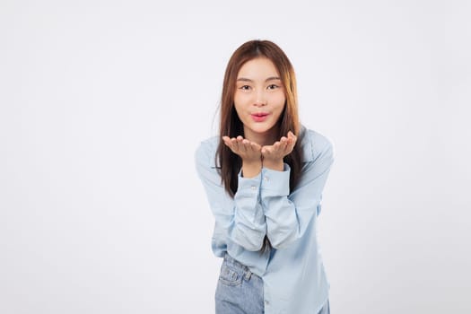 Woman blowing air kiss with both palms extended, happy woman shows affection with bright expression and loving gesture isolated on clean white studio background.