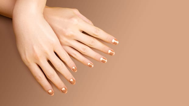 Beautiful Female Hands with bright Orange Manicure like Candy Corn on Yellow Background. Manicured Nails with Creative Gel Polish Design. Halloween Style