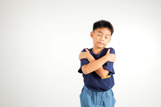 Happy young child smiling Asian boy hugging herself remember a moment studio short isolated on white background, Self care and self esteem concept, Lifestyle primary kid love yourself carefree