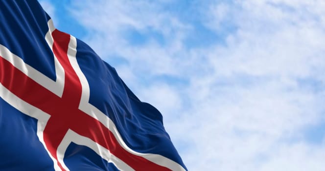 Close-up of Iceland national flag waving. Blue with a white cross and a red cross inside the white cross. 3d render illustration. Selective focus