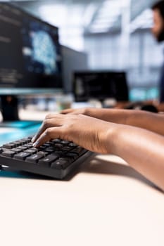 System administrator in server farm using AI systems, typing on keyboard, inputting data. Close up of data center technician using artificial intelligence parallel processing tech on computer