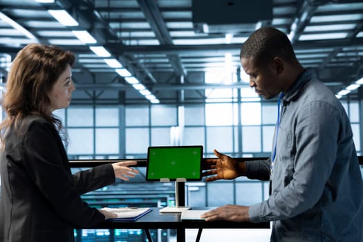 Software developers in data center using mockup tablet, observing analytics, reviewing equipment health. Server hub IT professionals talking, using chroma key device, adjusting system parameters