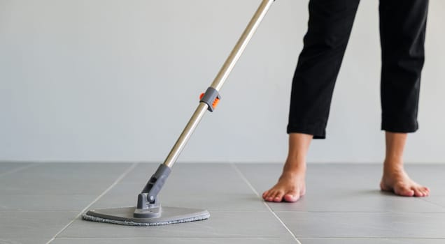 Woman mops the indoor floor, cleaning the front area of her home with a mop and rag. Housewife dedicated to maintaining cleanliness. Represents professional housekeeping and house maintenance concepts