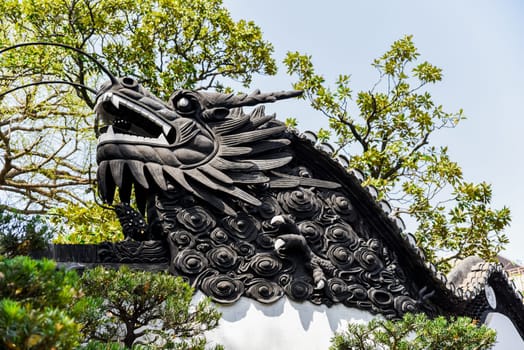 Shanghai, China - 1 April 2025: Dragon carving on the tiled roof of yuyuan garden, symbol of Chinese culture, harmony and classic garden design