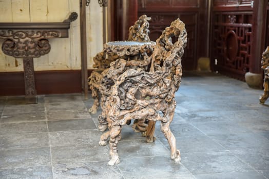 Shanghai, China - 1 April 2025: Intricately carved chairs and table made from banyan roots inside He Xu Hall of Dianchun Hall, Yuyuan Garden