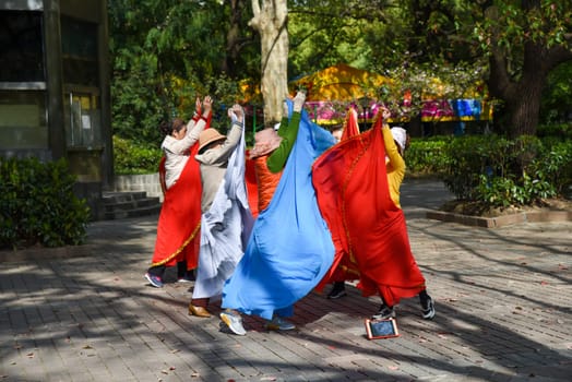 Shanghai, China - 1 April 2025: Senior Chinese women perform a colorful folk dance in People’s Park, gracefully moving in coordinated steps
