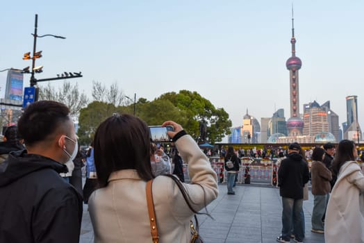 Shanghai, China – 1 April 2025: Chinese tourists take photos of the Pudong skyline with Oriental Pearl Tower, Jin Mao Tower and Shanghai Tower from Nanjing Road promenade