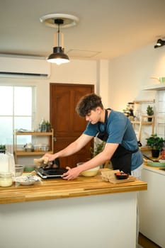Man using electric griddle to make pancakes in cozy kitchen.