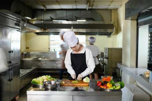 Culinary student practices chopping vegetables during a hands on cooking class in a kitchen.