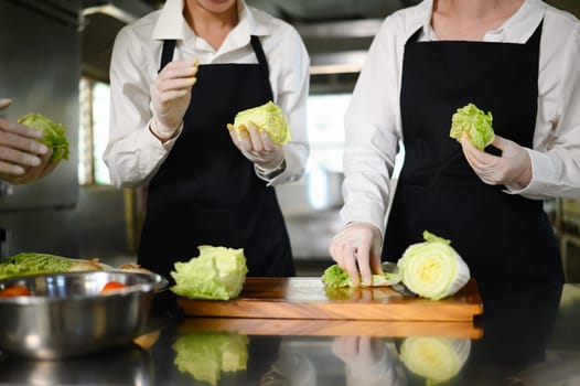 Young chefs practice slicing vegetables during a hands on cooking class at culinary school.